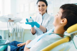 female dentist shows dentures to little boy QL97ED4