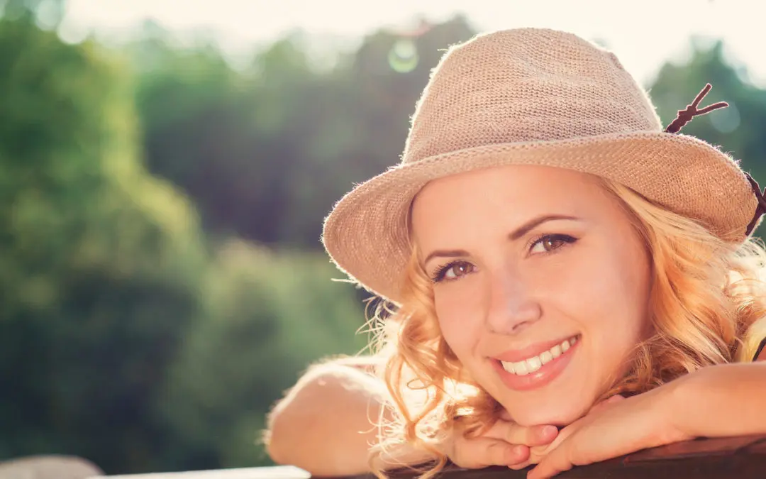 Blond woman, curly hair in green nature. Sunny summer