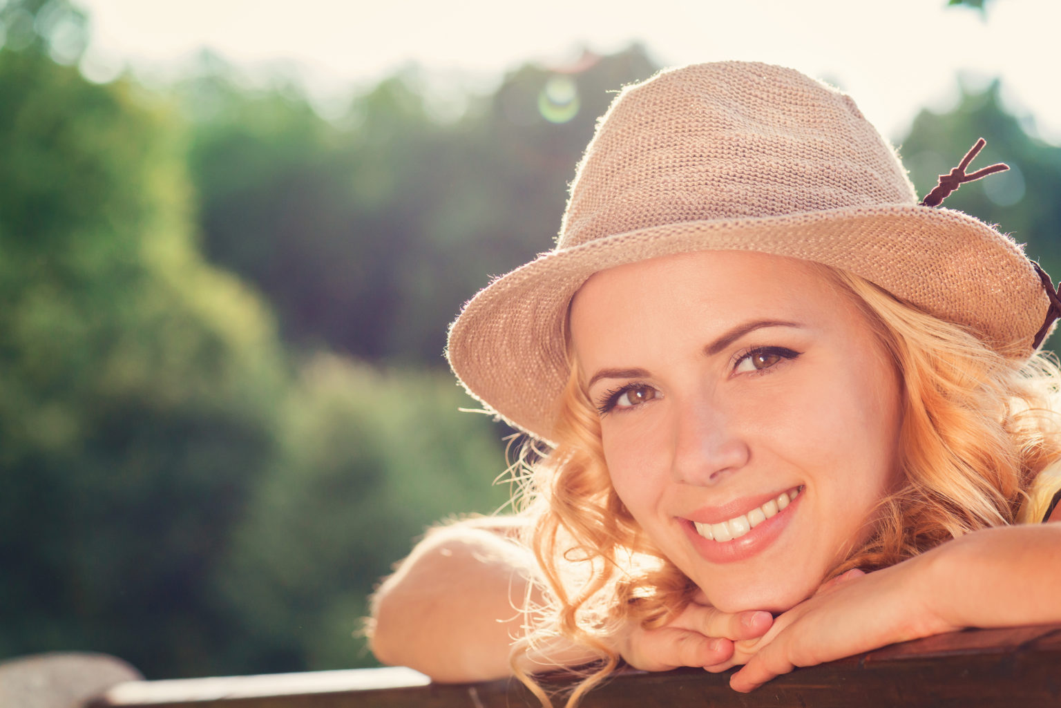 Blond woman, curly hair in green nature. Sunny summer