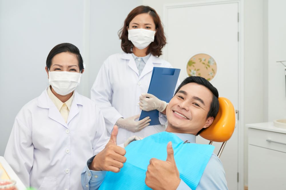 smiling-patient-and-doctors-in-dental-office-932G46R