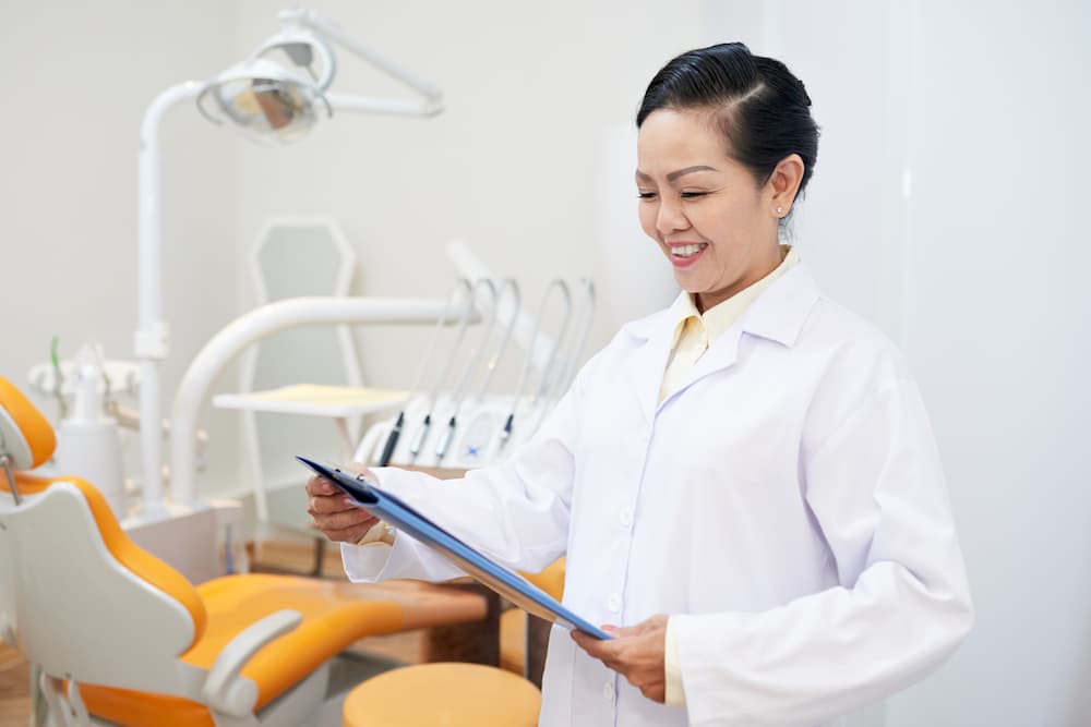 smiling dentist reading clipboard in office JN4YAUV 1